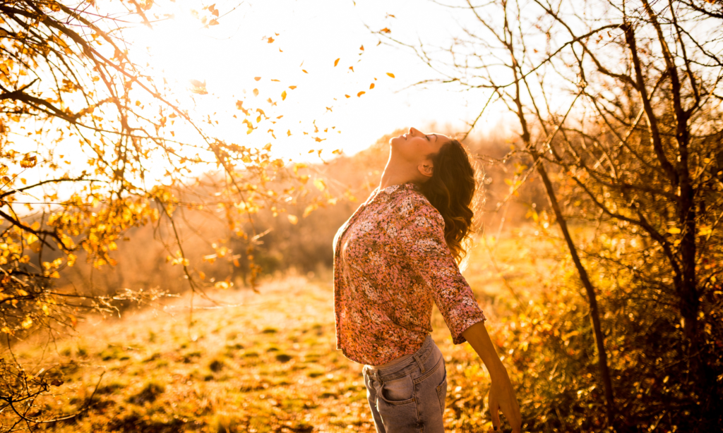 woman standing in a field at sunset with her face toward the sun and eyes closed - how to tap into your mom intuition