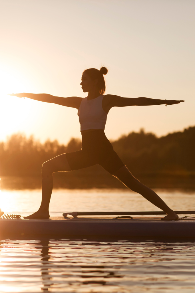 woman doing a yoga pose on a paddle board at sunset on a lake - how to say yes to doing what you want